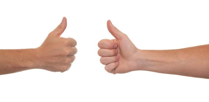 Two hands opposite to each other with thumbs up on white background