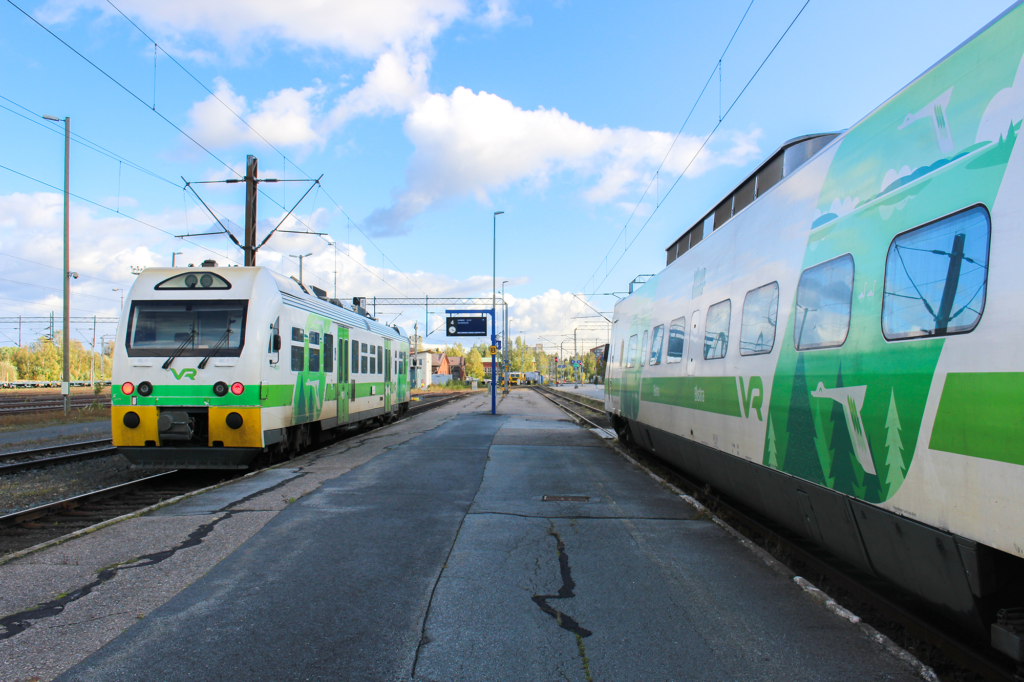 Kuvassa on kaksi VR:n valkovihreää junaa Seinäjoen rautatieasemalla. Junien taustalla on sininen ja osittainen pilvinen taivas.
