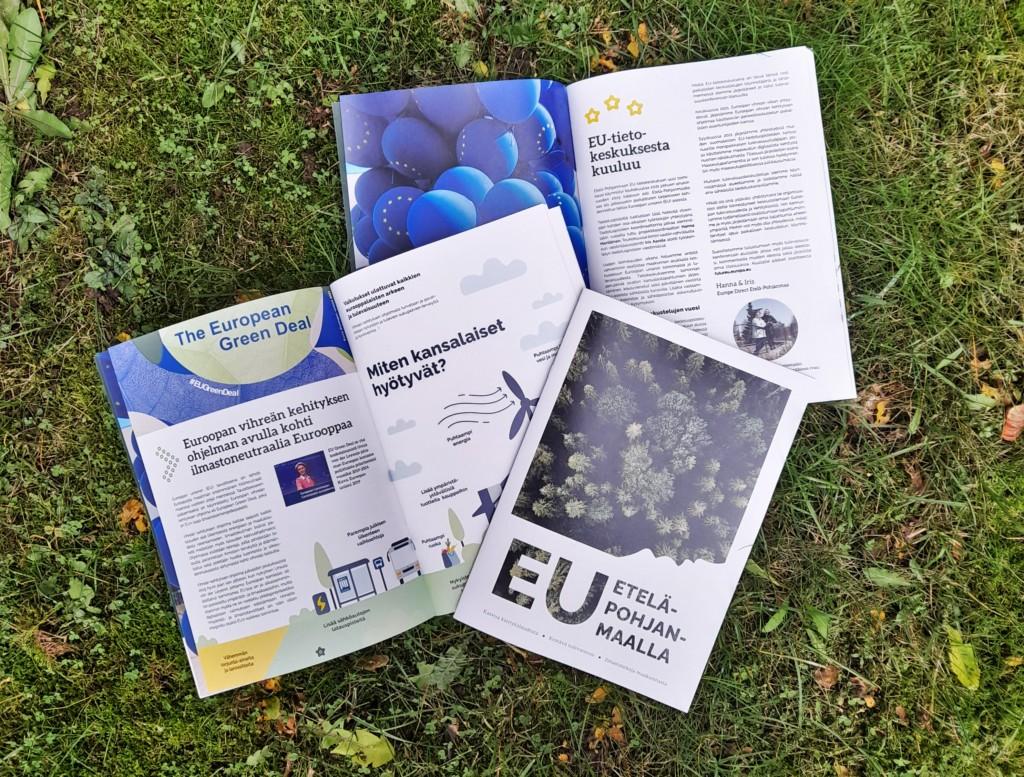 Kaksi aukinaista EU Etelä-Pohjanmaalla -lehteä kuvattuna ruohomatolla