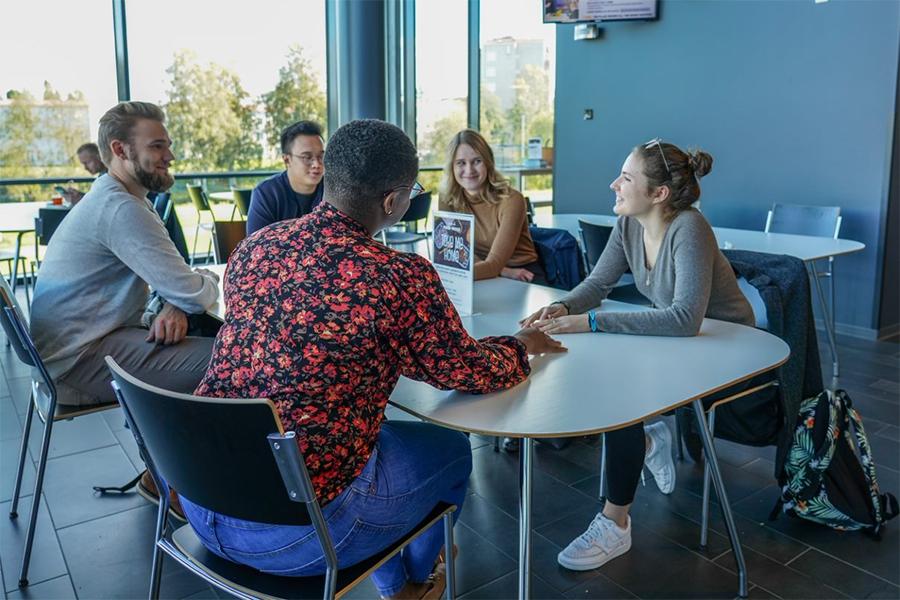 International students around the table in the premises of Seinäjoki University of Applied Sciences.