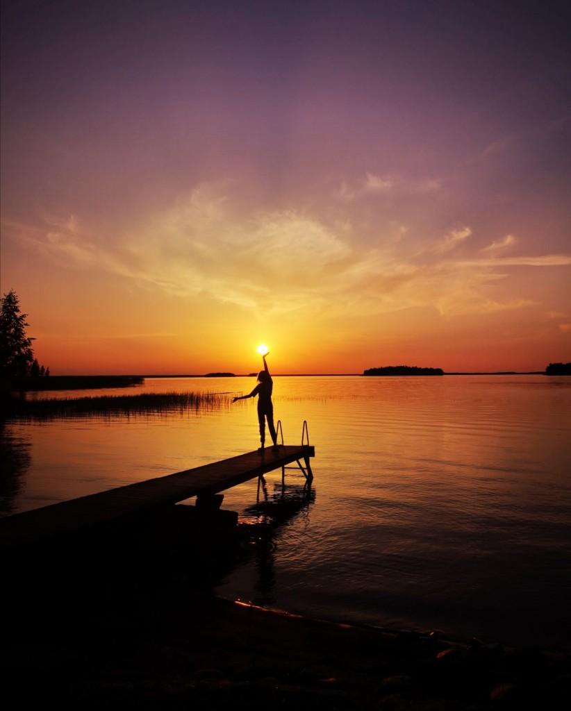 Tyttö auringonlaskussa laiturilla, taustalla Lappajärvi.