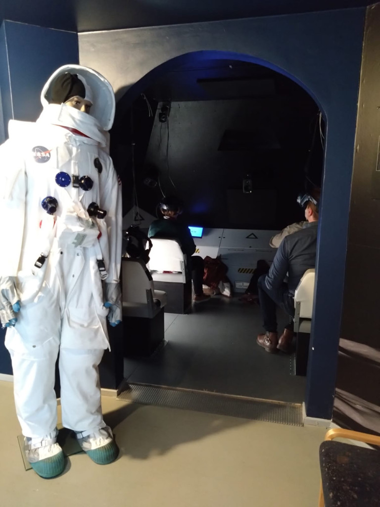 Etualalla avaruuspukuinen ihmishahmo ja takana näkymä avaruusaluksesta.