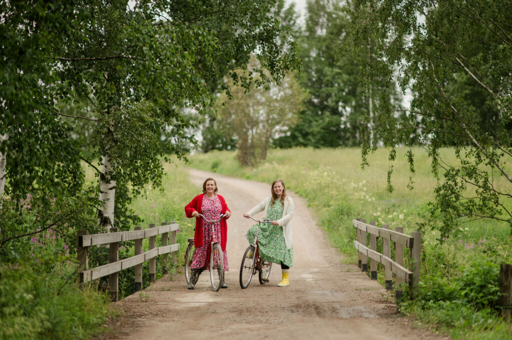 Sana-aarteita voivat olla esimerkiksi muistot pyöräilystä kesäsäisissä maisemissa, kuvassa kaksi naista pyöräilemässä koivujen vierellä.