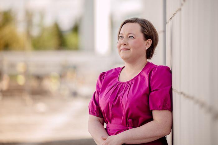 Henkilö nojaa ulkona seinään ja katsoo yläviistoon pois kamerasta.