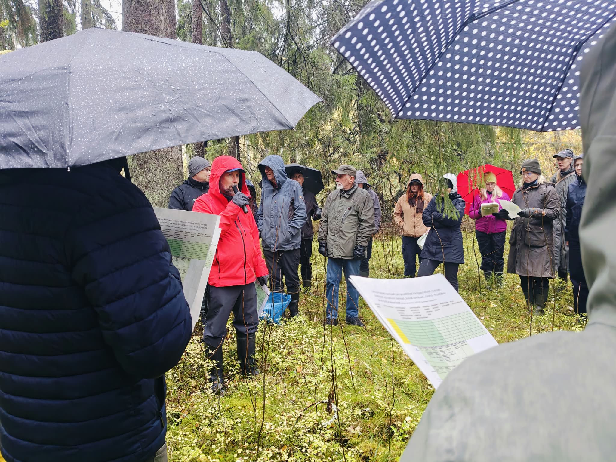 Ihmisiä sateisessa metsässä.